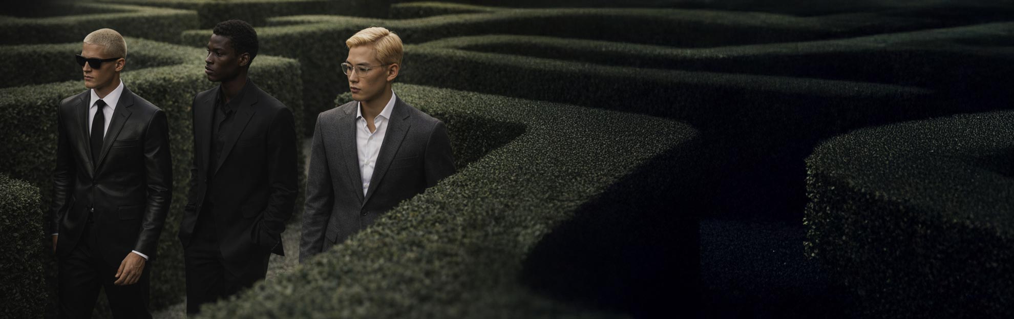 Three men in suits walking through a maze-like landscape.